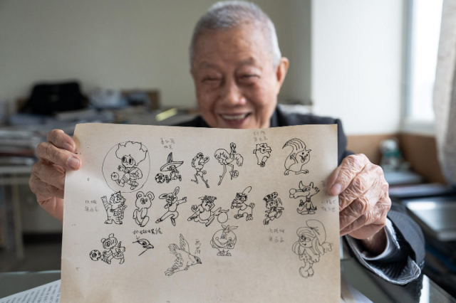 方唐展示自己摹画的历届体育大赛吉祥物手稿